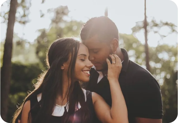 couple leaning into each other in nature with sunny background