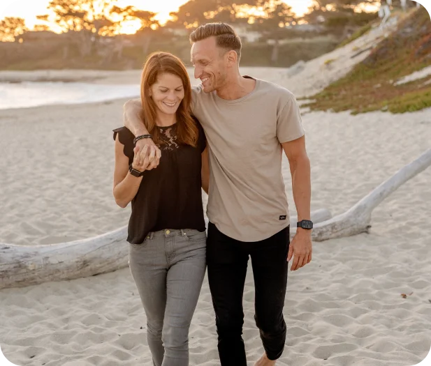 couple on the beach hugging each other and smiling while walking